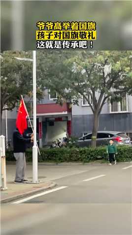 爷爷高举着国旗，孩子对国旗敬礼，这就是传承吧！