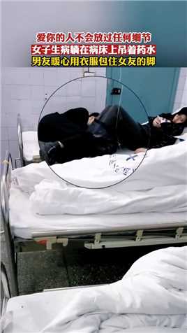 女子生病躺在病床上吊着药水，男友暖心用衣服包住女友的脚！