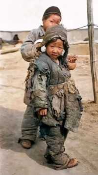 这张照片是民国时期拍摄的，前面这个小孩子，穿着破烂的衣服，这件衣服应该是他唯一的一件衣服。

