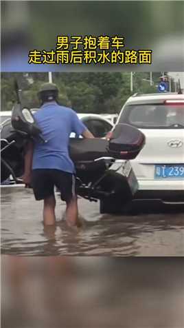 雨后路面积水，男子抱着车走