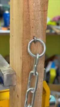 钉子敲弯固定链条，链条被牢牢固定在木块上