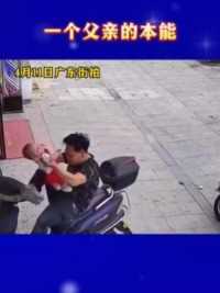一位父亲抱着孩子欲下摩托车时，摩托车倒翻瞬间，父亲本能的滚在地上护住孩子，