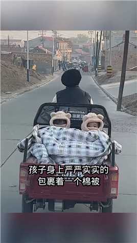 三轮车上坐着两个可爱的小孩