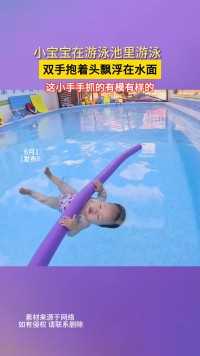 小宝宝在游泳池里游泳双手抱着头飘浮在水面这小手手抓的有模有样的