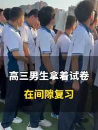 6月3日，山东济南。毕业典礼上高三男生拿着试卷在间隙复习，“真正努力过就没有遗憾”