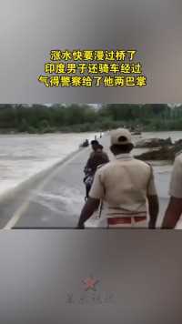 涨水快要漫过桥了 ，印度男子还骑车经过，气得警察给了他两巴掌