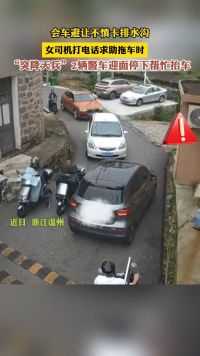 台州女司机会车避让不慎卡排水沟，2辆警车迎面停下帮忙抬车。