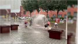 黑龙江哈尔滨大雨过后，路面有积水，学生们顺势过上了“泼水节”