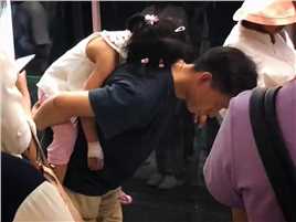 父亲为了让刚刚输完液的女儿睡得舒服点 弯着腰背着女儿 一动不动等地铁到站——这就是父爱 